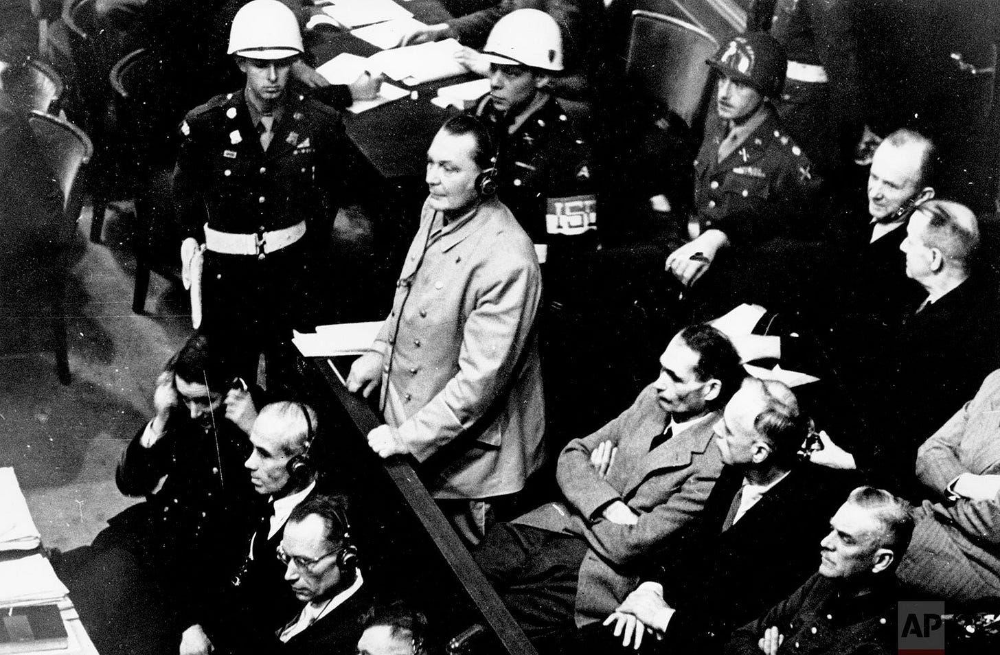 Reichsmarshal Hermann Goering defiantly stands in the prisoner's dock at the Nuremberg War Crimes Trial on November 21, 1945, pleading 'not guilty' to the International Military Tribunal Indictment. He wears court headphones, listening intently to the proceedings. Reichsmarshal Hermann Goering defiantly stands in the prisoner's dock at the Nuremberg War Crimes Trial on November 21, 1945, pleading 'not guilty' to the International Military Tribunal Indictment. He wears court headphones, listening intently to the proceedings.