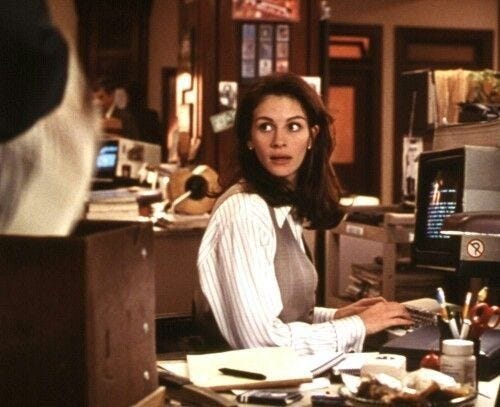 This may contain: a woman sitting at a desk in front of a computer