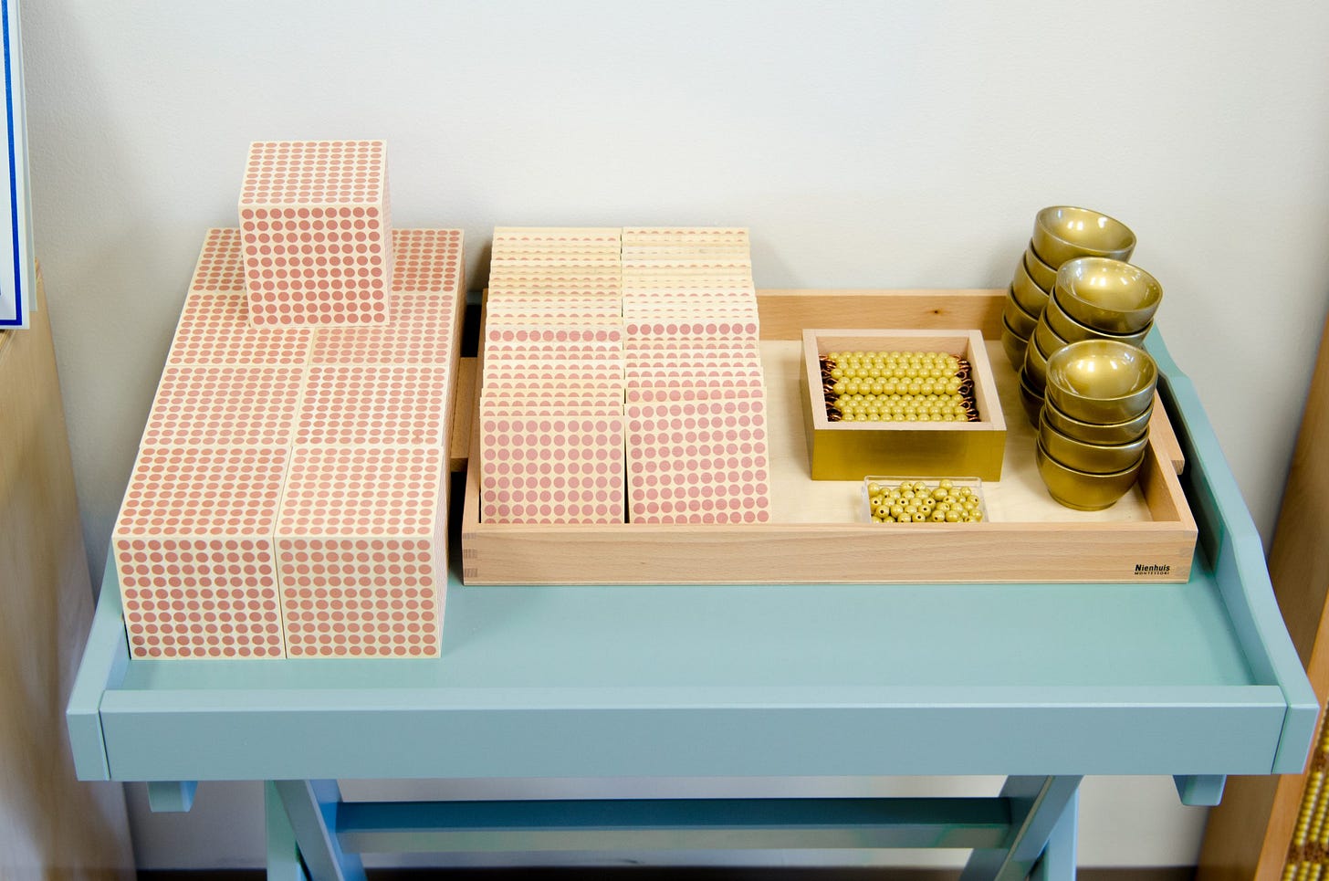 Nienhuis Montessori dot cabinet and golden bead materials on a classroom shelf — what is Montessori math material
