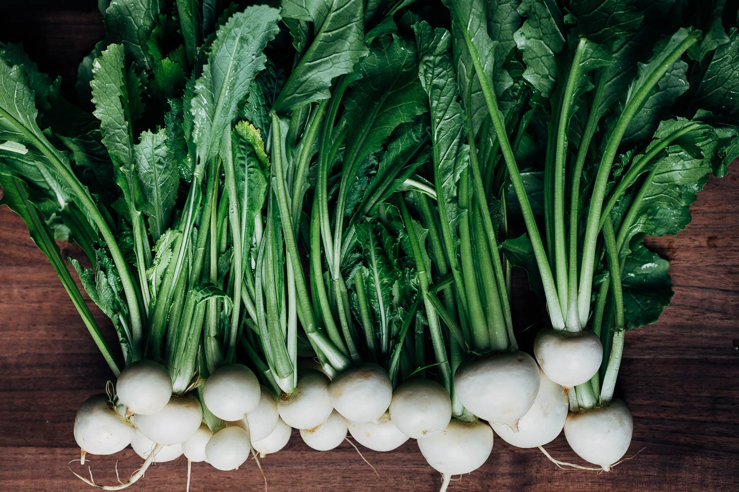 Hakurei turnips on a dark wood cutting board