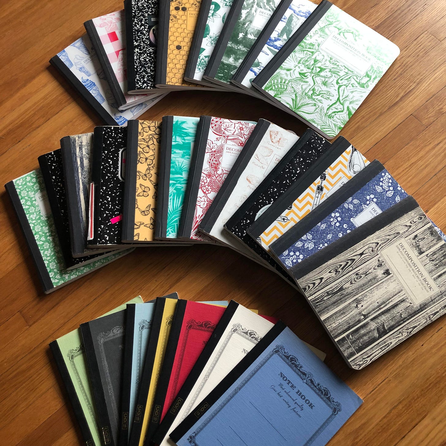 A bunch of notebooks on a wood floor.