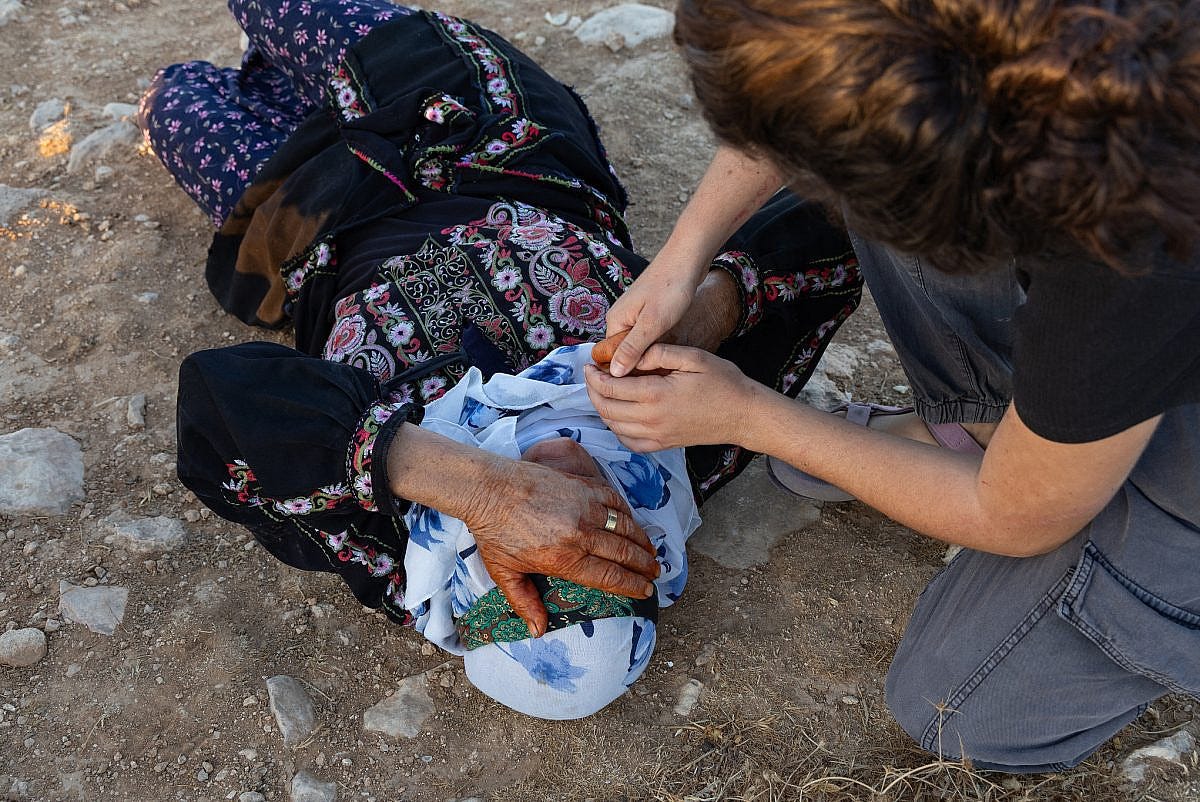 Wadha Abu Aram lies on the ground after a settler pepper‑sprayed her during an attack on her village of Qawawis, August 26, 2025. (Omri Eran Vardi)