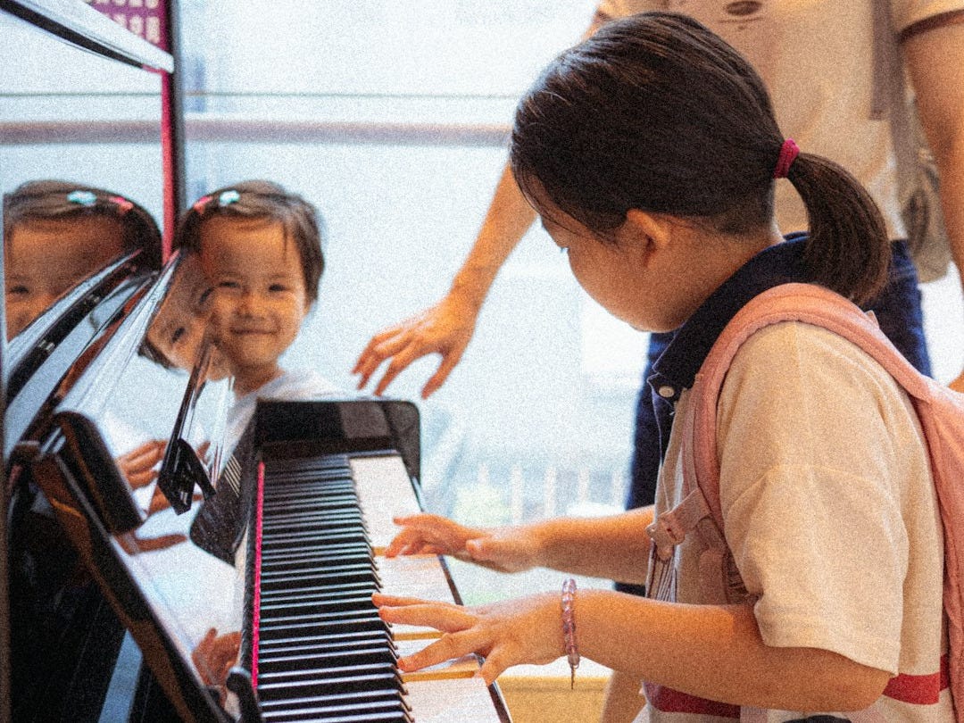 A group of young children sitting around a piano