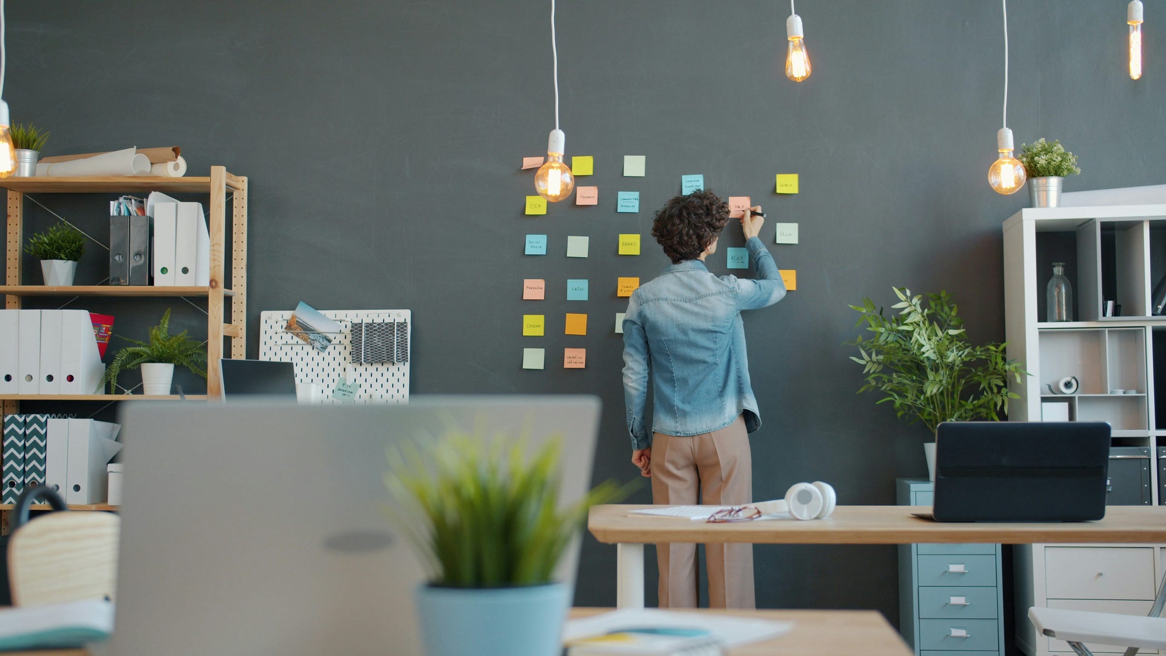 Photo of a person arranging sticky notes on a dark wall.