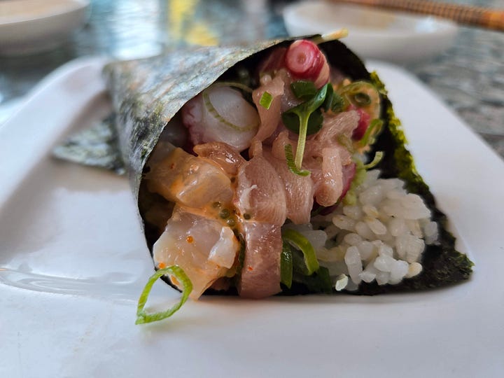 Closeup on the tops of hand rolls, their fillings peeking out over the rice.