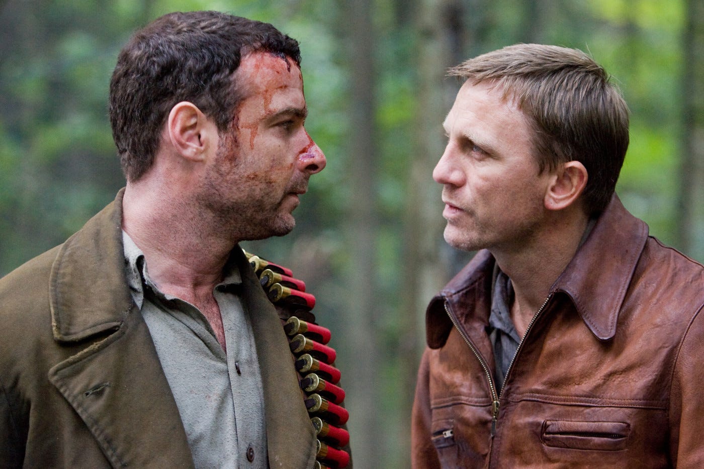 close up of Schreiber with blood on face talkign intently to Daniel Craig in a forest close up of Schreiber with blood on face talkign intently to Daniel Craig in a forest