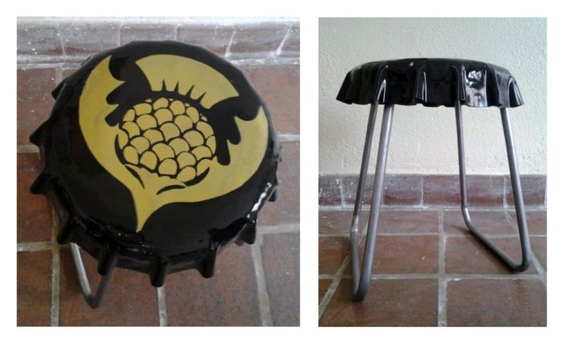 A stool with a seat shaped like a bottle cap with a black cap with a gold winged thistle.