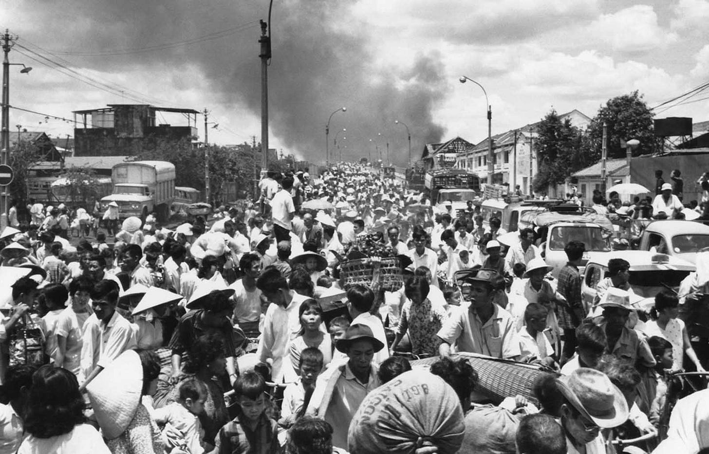May 7, 1968, Saigon: Smoke billows from the city's southwest as residents flee across a bridge, escaping intense urban combat between Viet Cong and South Vietnamese forces. May 7, 1968, Saigon: Smoke billows from the city's southwest as residents flee across a bridge, escaping intense urban combat between Viet Cong and South Vietnamese forces.