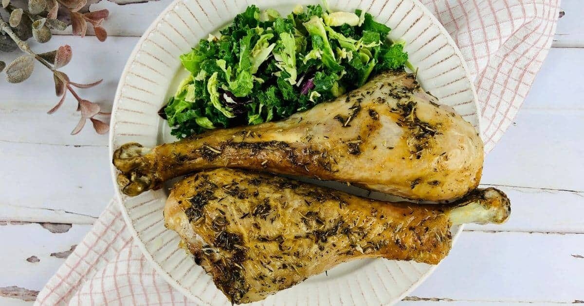 Two fully cooked air fryer turkey legs on a plate with garnish.