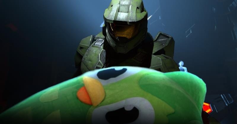 A meme recreation of a Halo Infinite cut-scene scene with Escharum. Master Chief stands over a fallen Duolingo, with The Weapon in the background.