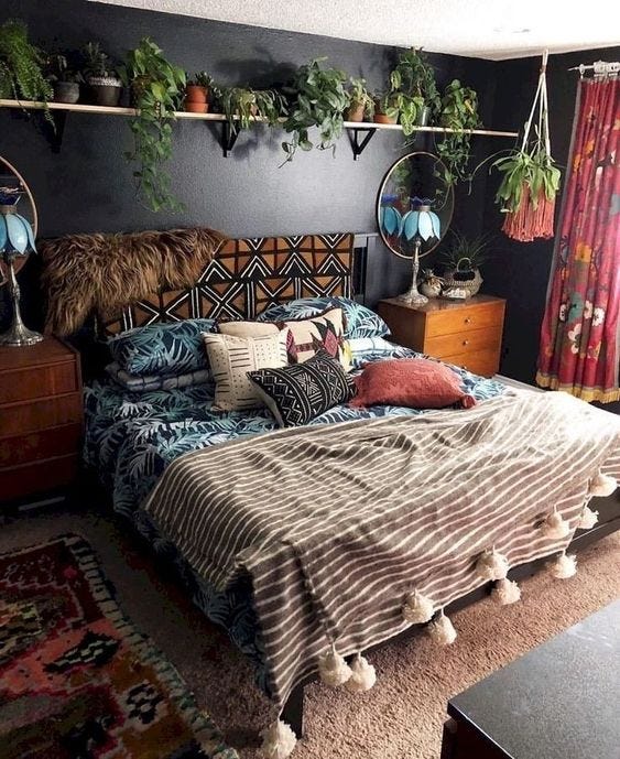 A bedroom with a large bed covered in pillows and blankets of various patterns and textures, soft-lookingcarpet, and a shelf above the bed lined with different kinds of houseplants A bedroom with a large bed covered in pillows and blankets of various patterns and textures, soft-lookingcarpet, and a shelf above the bed lined with different kinds of houseplants