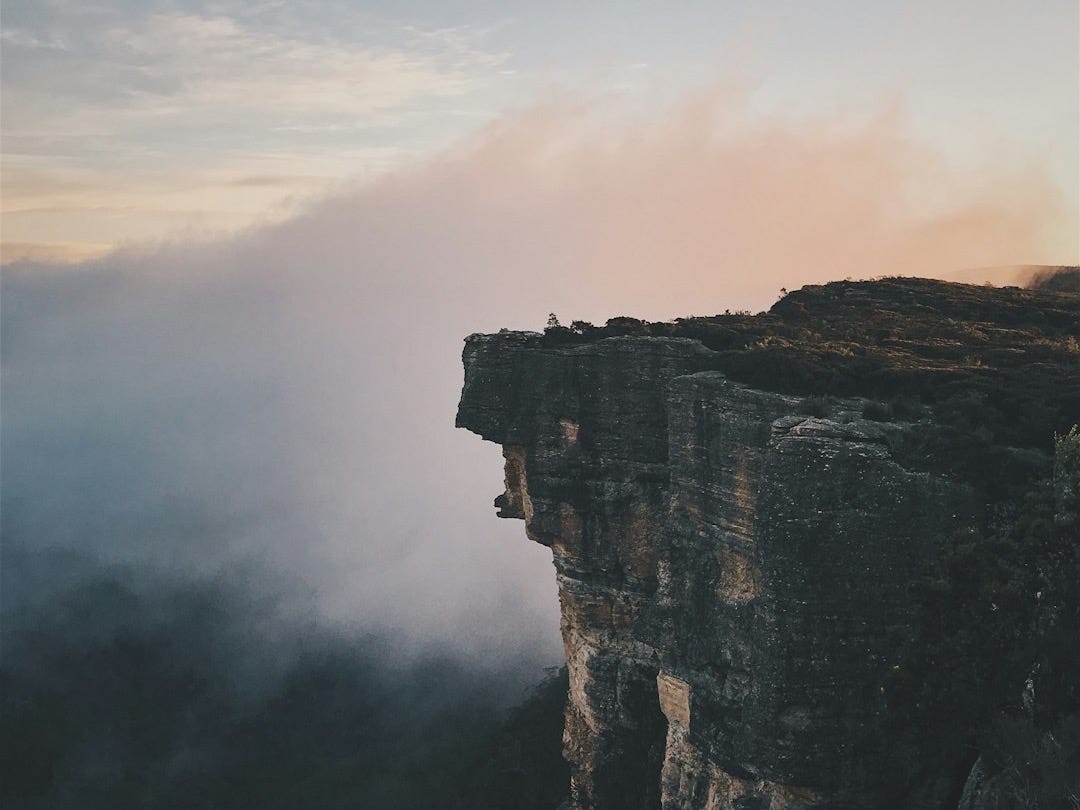 person sitting on mountain cliff