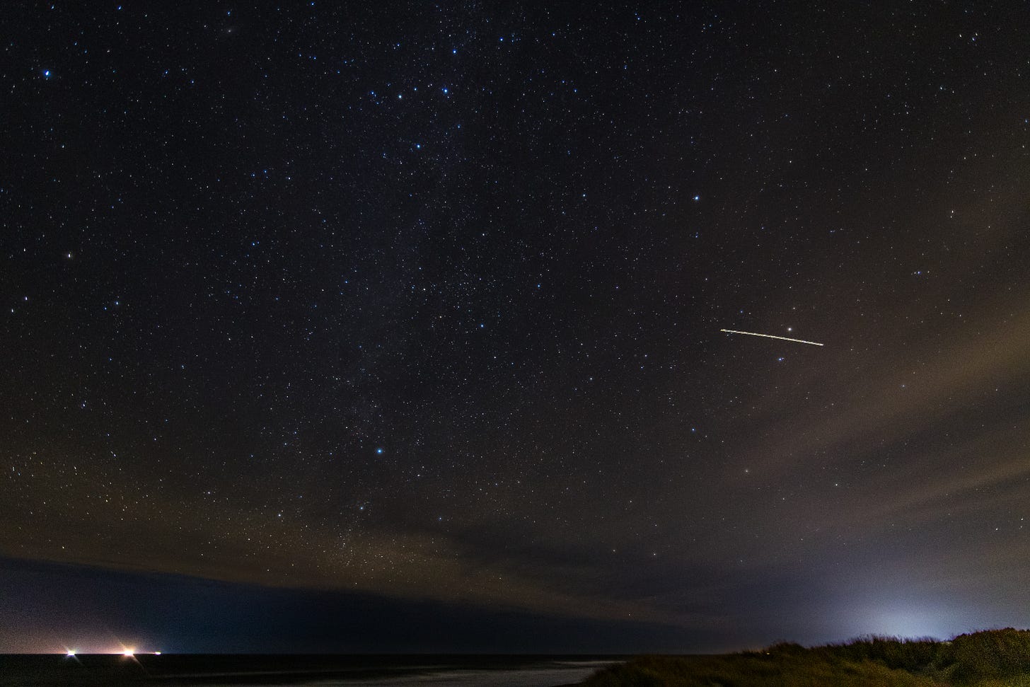 Milky Way over the Pacific Ocean from the coast, with an airplane light streak