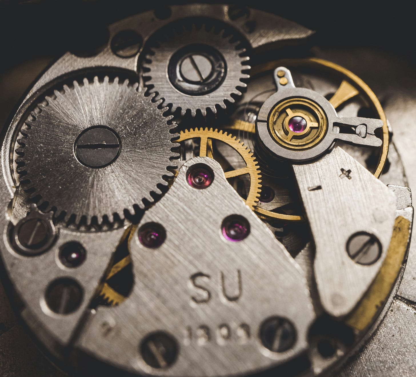 a close-up view of a watch movement showing multiple gears and parts a close-up view of a watch movement showing multiple gears and parts