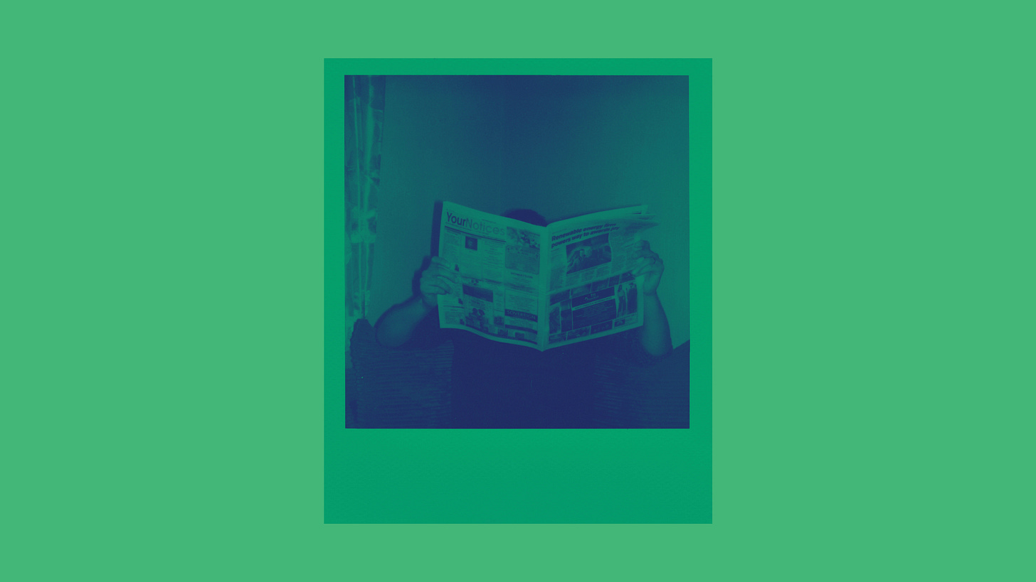 A person reading a newspaper. Face obscured. A person reading a newspaper. Face obscured.