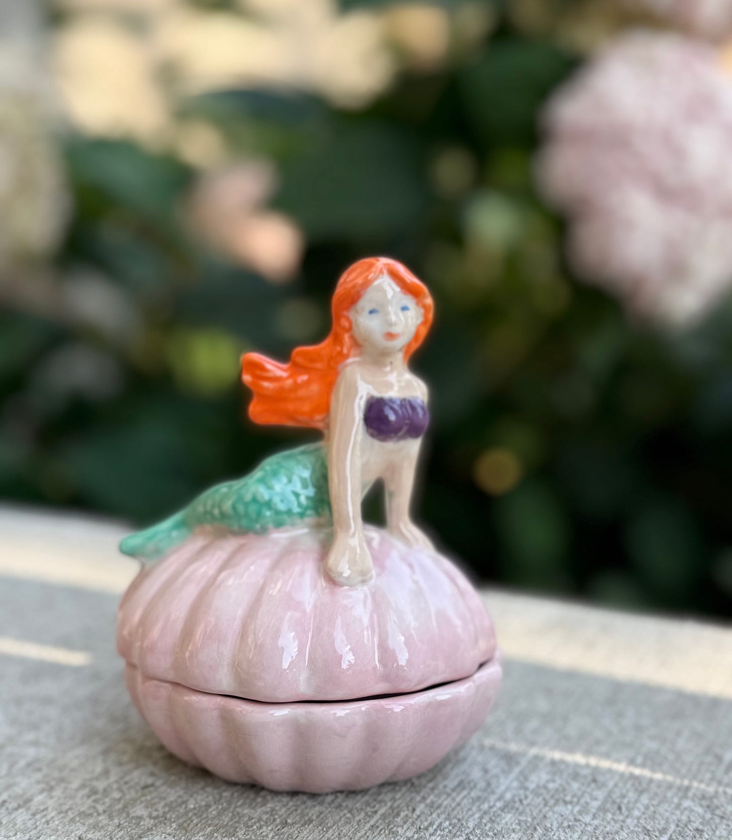 Painted ceramic mermaid on a pearly pink shell