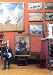 A person standing in front of a wall with paintings on it

Description automatically generated with medium confidence
