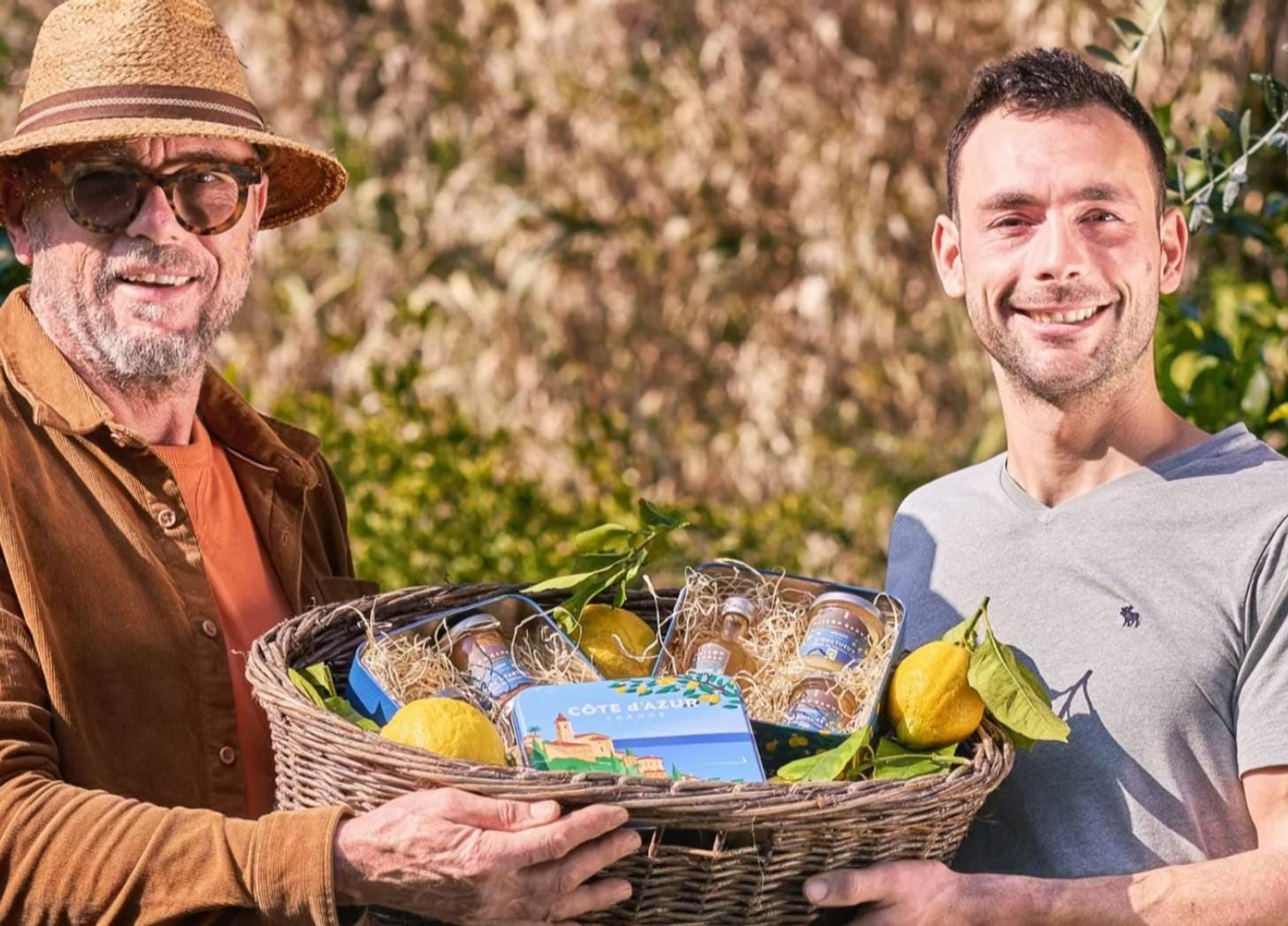 Laurent and Adrien Gannac, father and son lemon producers in Menton, holding a basket of Maison Gannac citrus products.