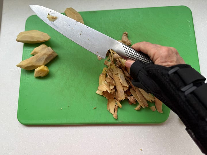 1. Hand in splint holding knife over ginger on a cutting board. 2. Man using a food process or to grate gi nger.