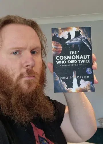 Phillip Carter holds aloft a copy of THE COSMONAUT WHO DIED TWICE, his science fiction novella