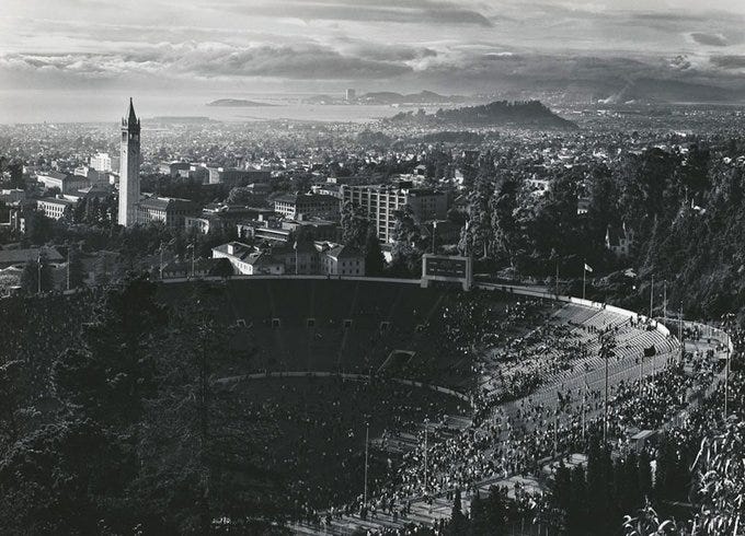 Memorial Stadium and the Campanile are pictured in this dramatic black-and-white photograph of the UC Berkeley campus. The bay serves as the backdrop.