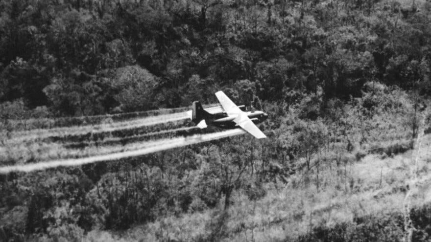A U.S. Air Force C-123 sprays herbicides on dense jungle beside a South Vietnamese highway on May 18, 1966. This aircraft is the last in a formation of three. Spray from the other two planes can be seen ahead. A U.S. Air Force C-123 sprays herbicides on dense jungle beside a South Vietnamese highway on May 18, 1966. This aircraft is the last in a formation of three. Spray from the other two planes can be seen ahead.