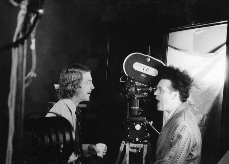 This may contain: black and white photograph of two men in front of a camera