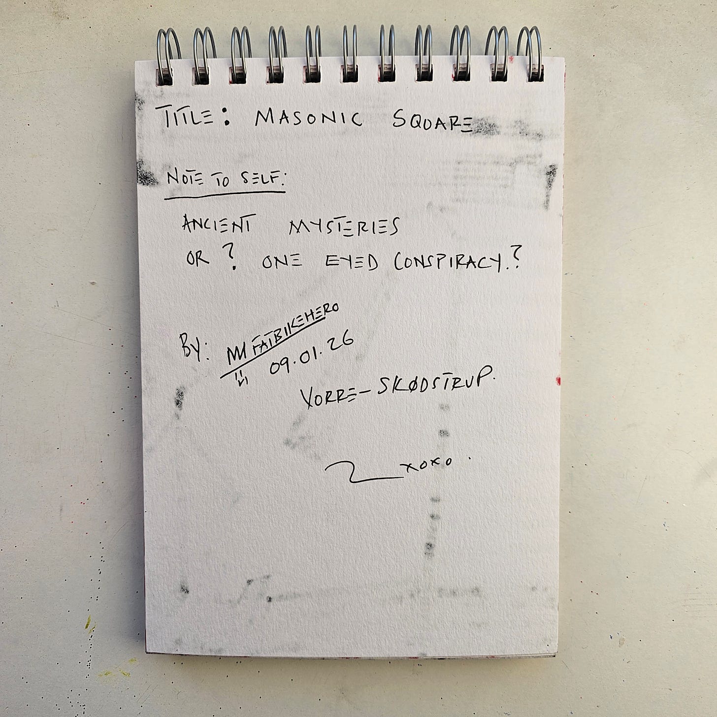 Alt Text: The reverse side of a sketchbook page by artist FatbikeHero. Handwritten text in black ink reads "TITLE: MASONIC SQUARE," "NOTE TO SELF: ANCIENT MYSTERIES OR? ONE EYED CONSPIRACY?" and "BY: M FATBIKEHERO." The date "09.01.26" and location "VORRE - SKØDSTRUP" are inscribed below. Alt Text: The reverse side of a sketchbook page by artist FatbikeHero. Handwritten text in black ink reads "TITLE: MASONIC SQUARE," "NOTE TO SELF: ANCIENT MYSTERIES OR? ONE EYED CONSPIRACY?" and "BY: M FATBIKEHERO." The date "09.01.26" and location "VORRE - SKØDSTRUP" are inscribed below.