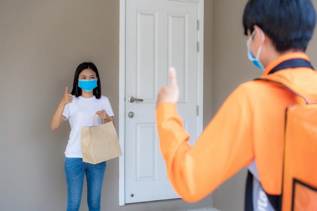 Asian woman pick up delivery food bag from door knob and thumb up form contactless or Asian woman pick up delivery food bag from door knob and thumb up form contactless or
