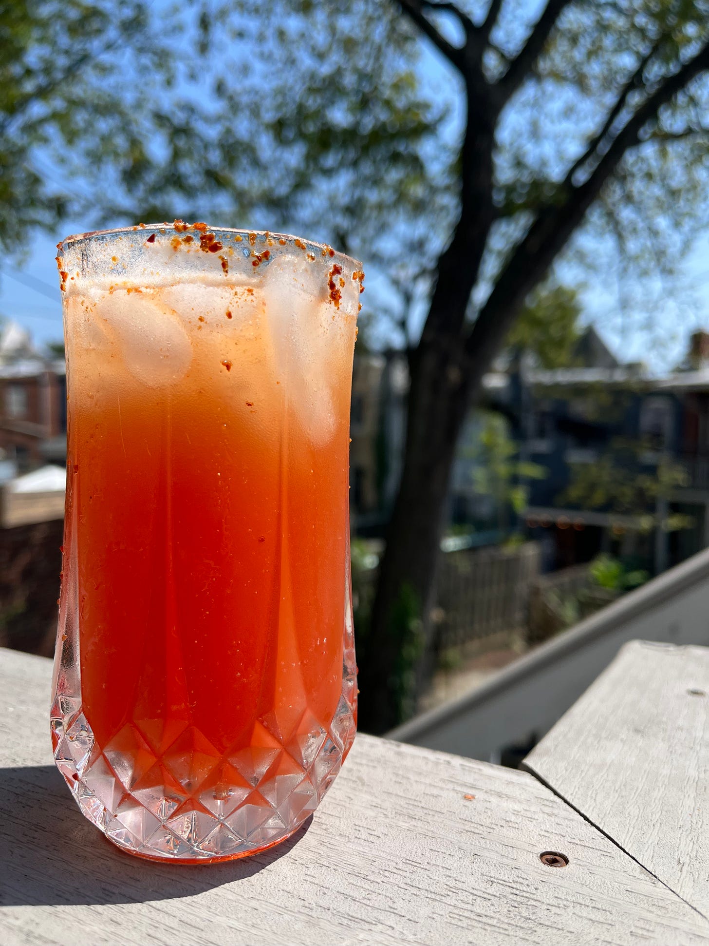 A michelada with a tajin rim served outside on a deck