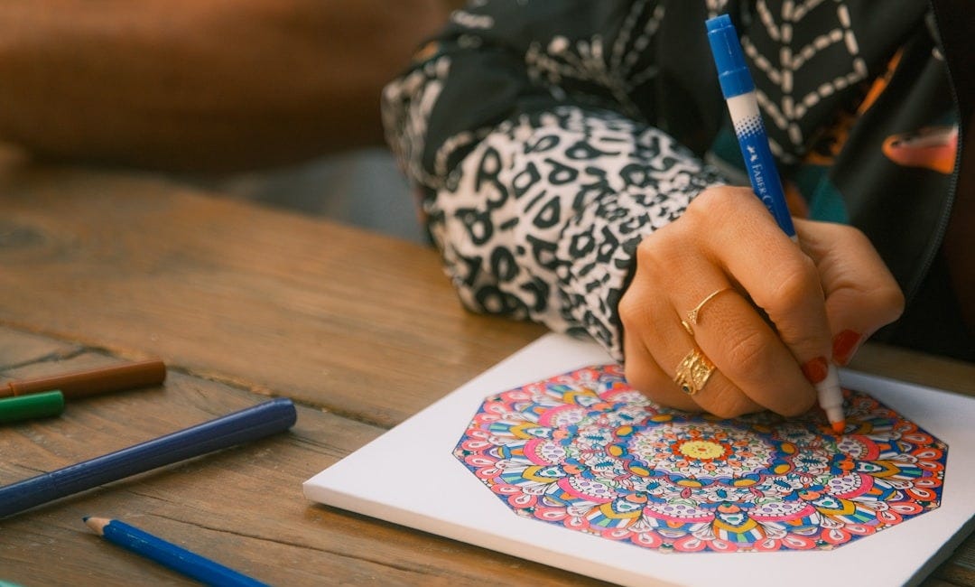 Person coloring a mandala with markers on paper