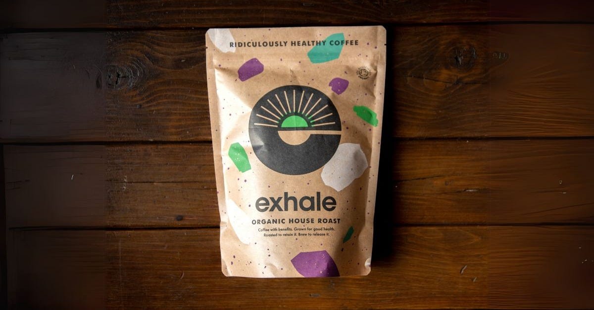 A pouch of Exhale Organic House Roast on a dark wooden background