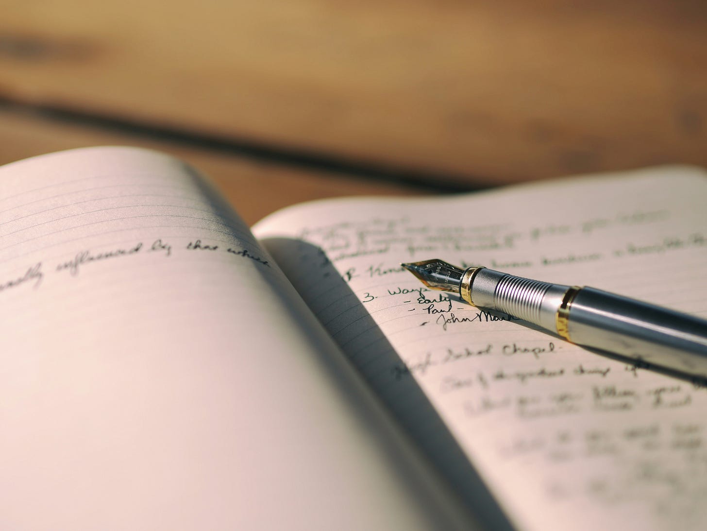 artistic image of a hand-written journal with fountain pen laid across the page