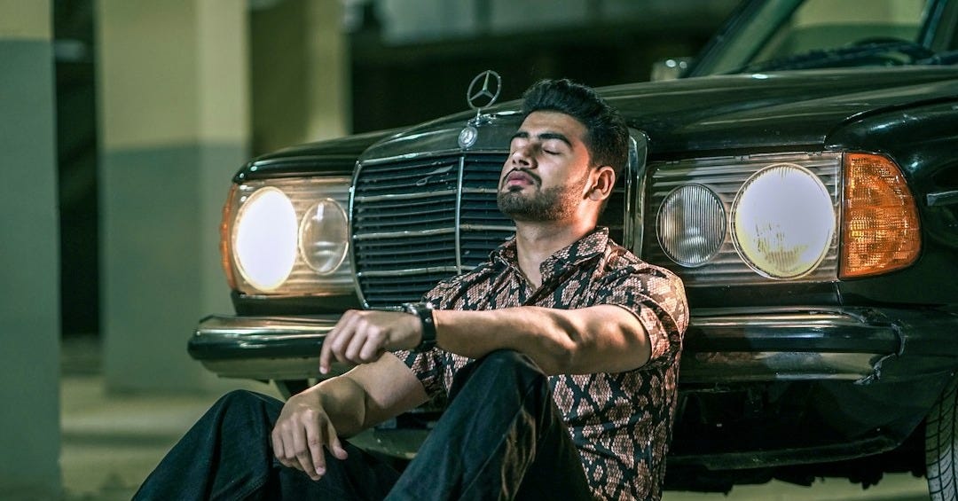 a man sitting on the ground next to a car