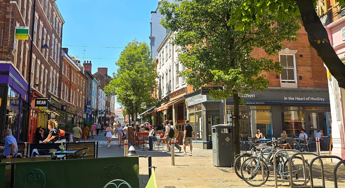 A city street with colourful shops and trees A city street with colourful shops and trees