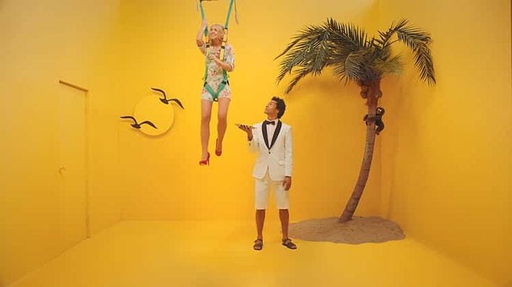 This may contain: two people in white suits and one is holding a baby while the other holds a palm tree