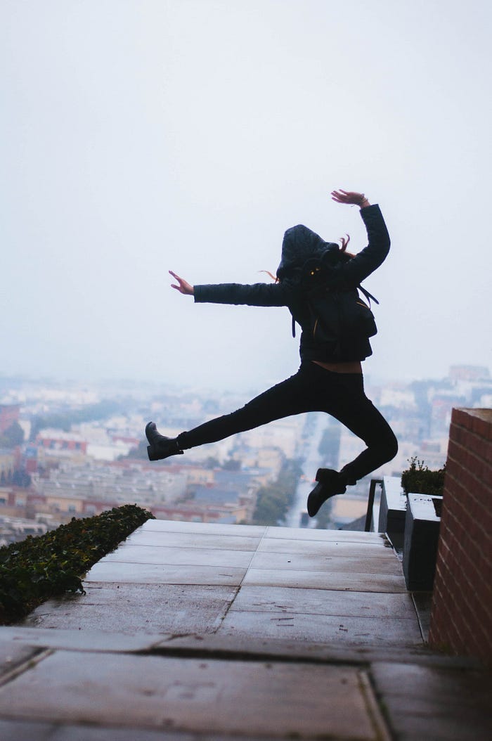 a woman, viewed from the back, jumping excitedly on a roof a woman, viewed from the back, jumping excitedly on a roof