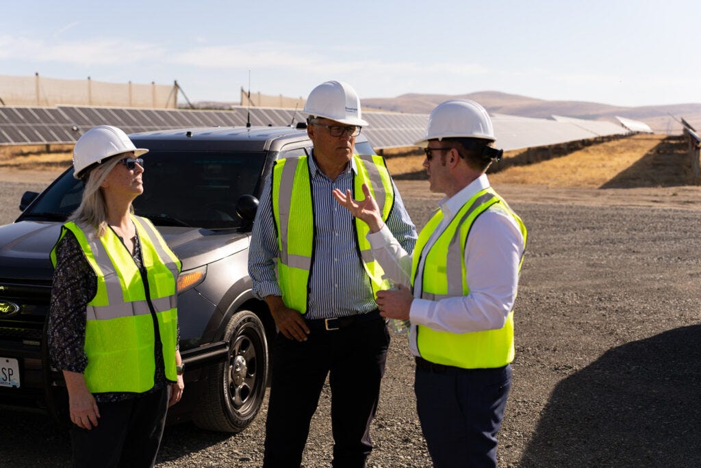 Jay Inslee talking to two people at a solar farm.