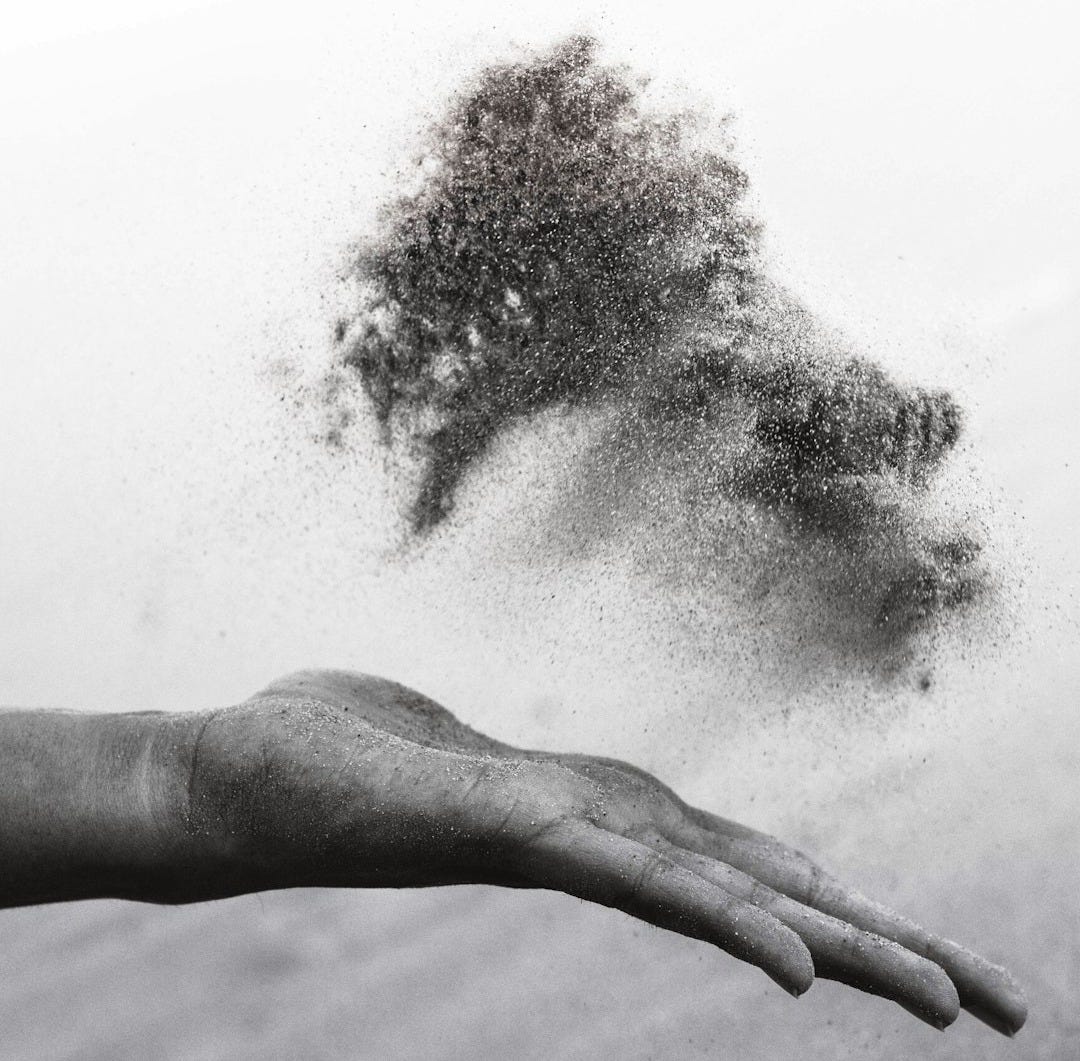 grayscaled photography of person's hand spreading sand