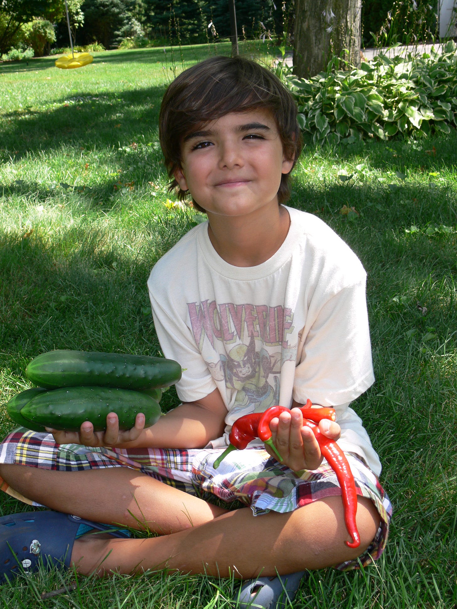 a boy holding cucumbers and peppers