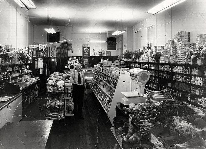 This may contain: an old black and white photo of a woman in the produce section of a grocery store