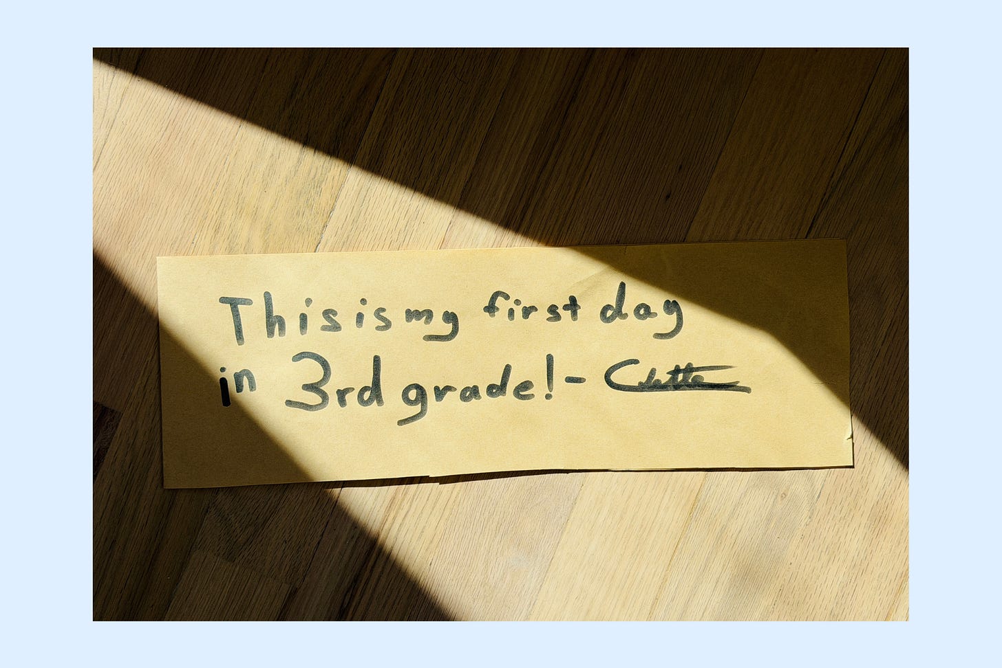 A child's handwriting on lined paper reading "my name is Colette and this is my first day of third grade," shot flat from above in window light A child's handwriting on lined paper reading "my name is Colette and this is my first day of third grade," shot flat from above in window light