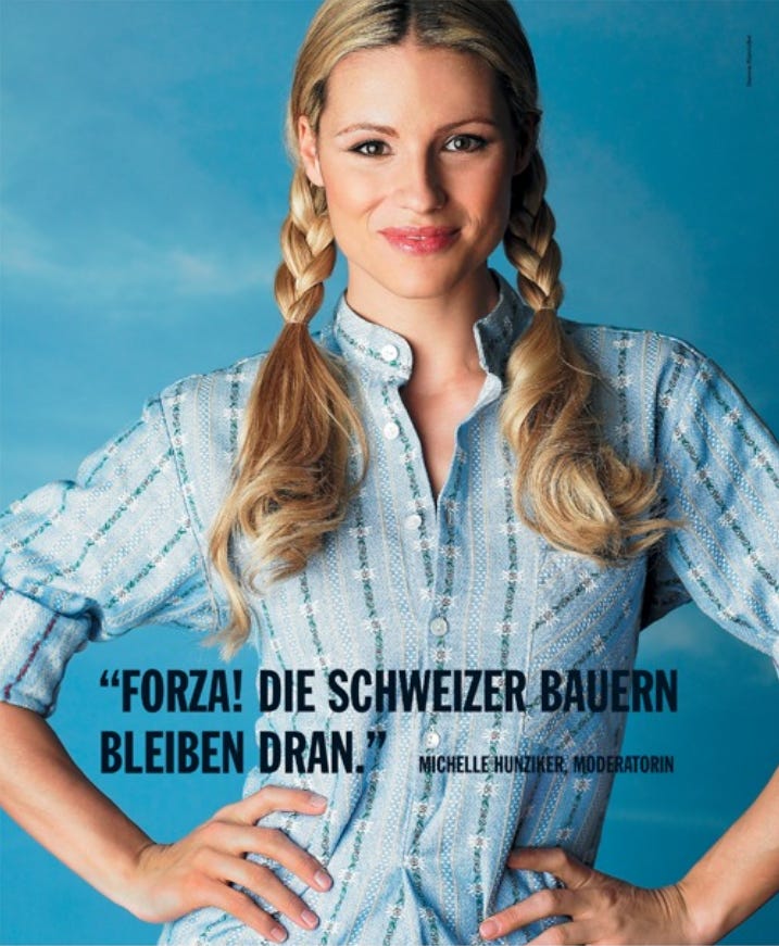 Porträt der Fernsehmoderatorin Michelle Hunziker mit zwei geflochtenen blonden Zöpfen im hellblauen, traditionell wirkenden Edelweisshemd vor blauem Hintergrund. Unten der Ausruf: «Forza! Die Schweizer Bauern bleiben dran.» Porträt der Fernsehmoderatorin Michelle Hunziker mit zwei geflochtenen blonden Zöpfen im hellblauen, traditionell wirkenden Edelweisshemd vor blauem Hintergrund. Unten der Ausruf: «Forza! Die Schweizer Bauern bleiben dran.»