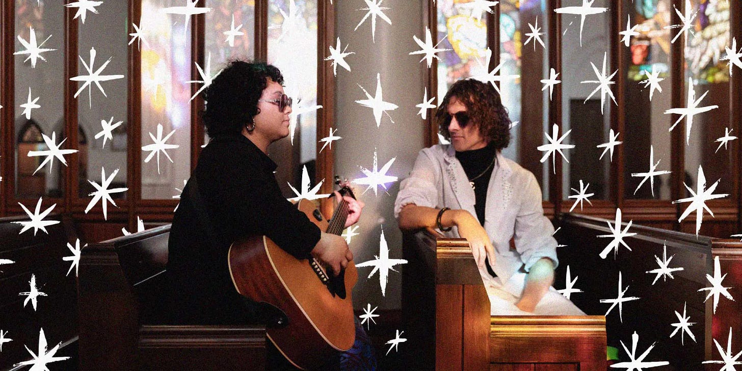 Maretta Brown has short curly black hair and plays the guitar, and Ari Kerssens wears a white suit. They are seated in pews surrounded by white graphic stars. Maretta Brown has short curly black hair and plays the guitar, and Ari Kerssens wears a white suit. They are seated in pews surrounded by white graphic stars.