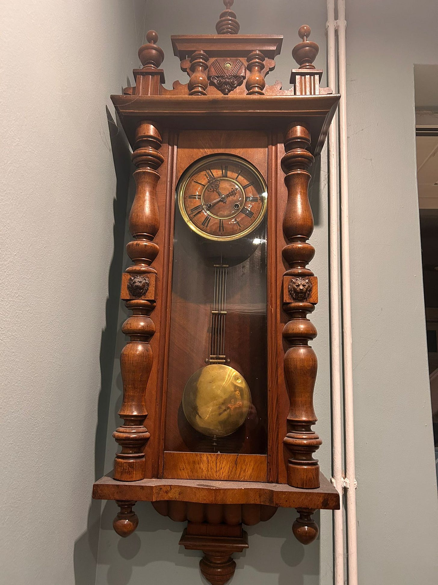Antique wooden wall clock from 1911 with pendulum and carved columns - eerie domestic object linked to ghost stories and family folklore in Tarot DMs conversation. Antique wooden wall clock from 1911 with pendulum and carved columns - eerie domestic object linked to ghost stories and family folklore in Tarot DMs conversation.