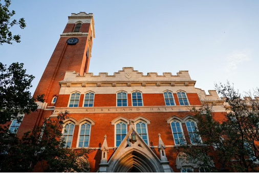 Large red brick academic building with clock tower and the words Kirkland Hall across the front at sunset