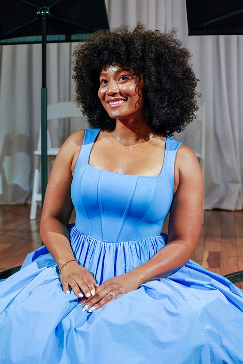 Dr. Mysia Anderson-White in a blue dress sitting on stage with music stands behind her.