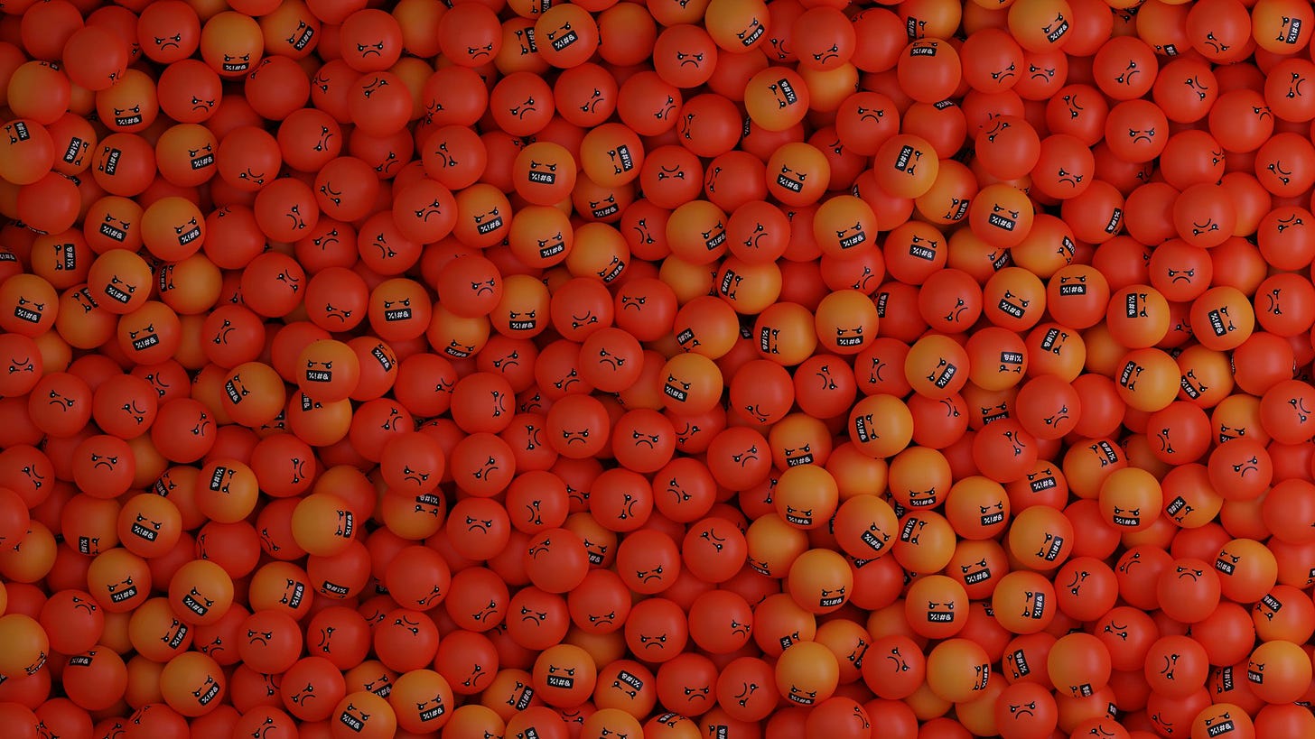A large pile of orange tennis balls with the 'swearing' emoji painted on them