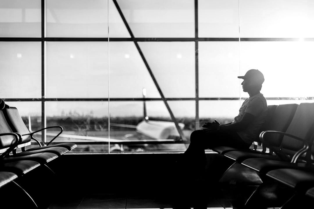 man sitting on gang chair near window man sitting on gang chair near window