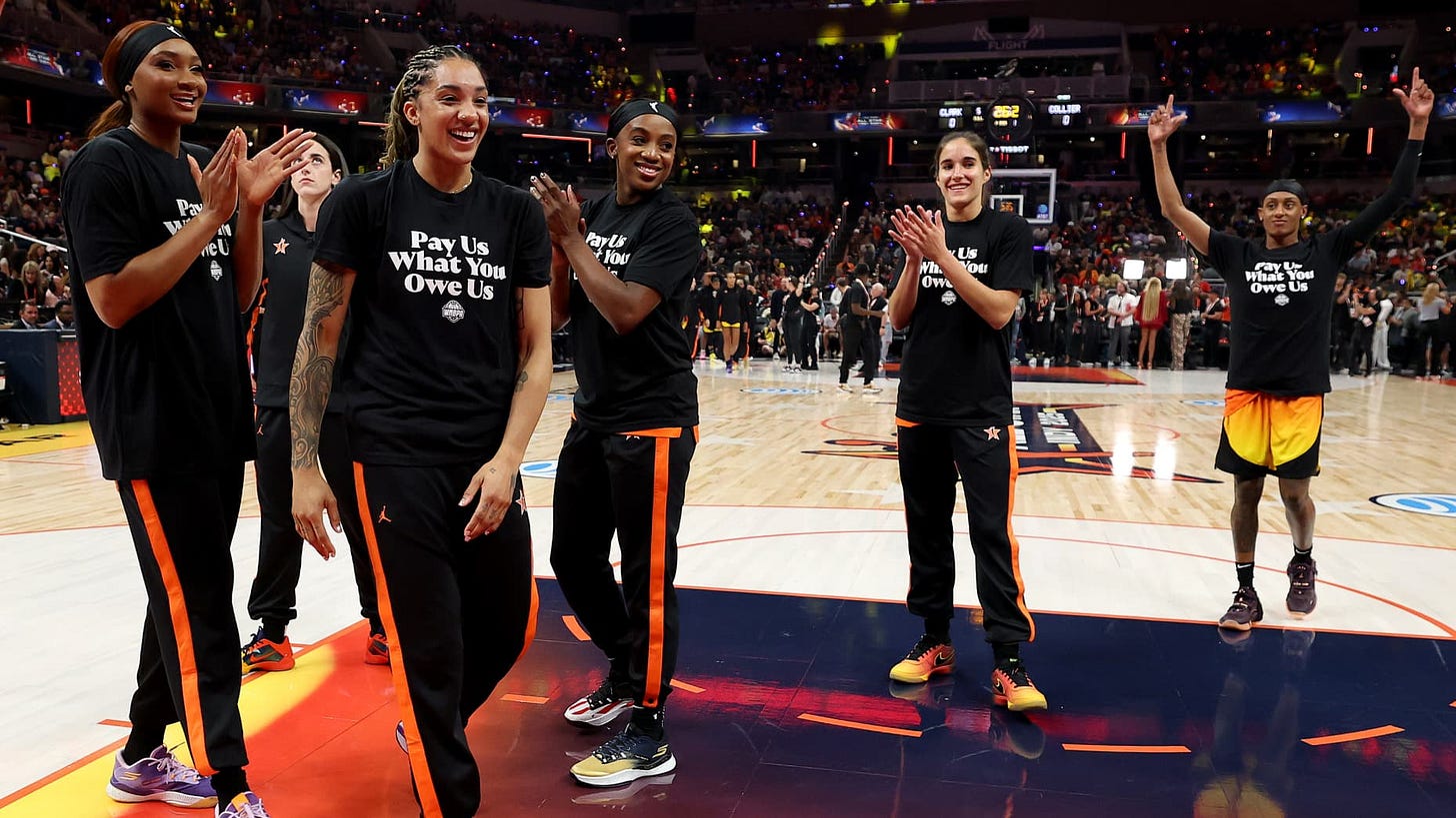INDIANAPOLIS, INDIANA - JULY 19: Kiki Iriafen #44 of the Washington Mystics, Gabby Williams #5 of the Seattle Storm, Jackie Young #0 of the Las Vegas Aces, Sonia Citron #2 of the Washington Mystics and Brittney Sykes #15 of the Washington Mystics wear shirts saying "Pay us what you owe us" prior to the 2025 AT&T WNBA All-Star Game at Gainbridge Fieldhouse on July 19, 2025 in Indianapolis, Indiana. NOTE TO USER: User expressly acknowledges and agrees that, by downloading and or using this photograph, User is INDIANAPOLIS, INDIANA - JULY 19: Kiki Iriafen #44 of the Washington Mystics, Gabby Williams #5 of the Seattle Storm, Jackie Young #0 of the Las Vegas Aces, Sonia Citron #2 of the Washington Mystics and Brittney Sykes #15 of the Washington Mystics wear shirts saying "Pay us what you owe us" prior to the 2025 AT&T WNBA All-Star Game at Gainbridge Fieldhouse on July 19, 2025 in Indianapolis, Indiana. NOTE TO USER: User expressly acknowledges and agrees that, by downloading and or using this photograph, User is